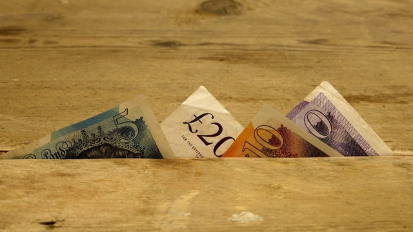 British currency notes partially visible from a wooden surface