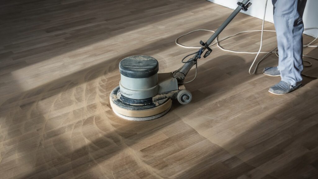 Person using a floor buffer on wooden flooring