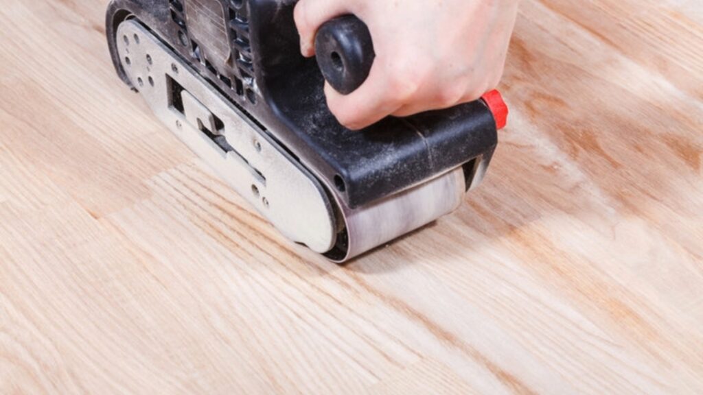 Hand using an electric sander on a wooden surface